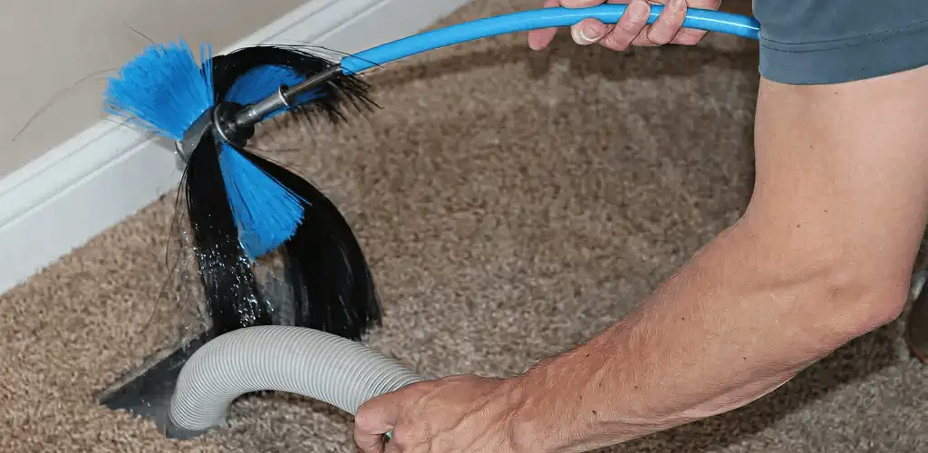 Dryer vent cleaning technician brushing lint from a vent line in Toledo, OH