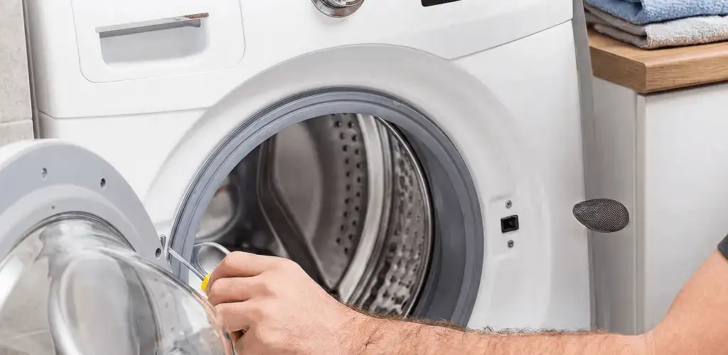 Handyman repairing a front-load washing machine and inspecting the drum in Toledo, OH