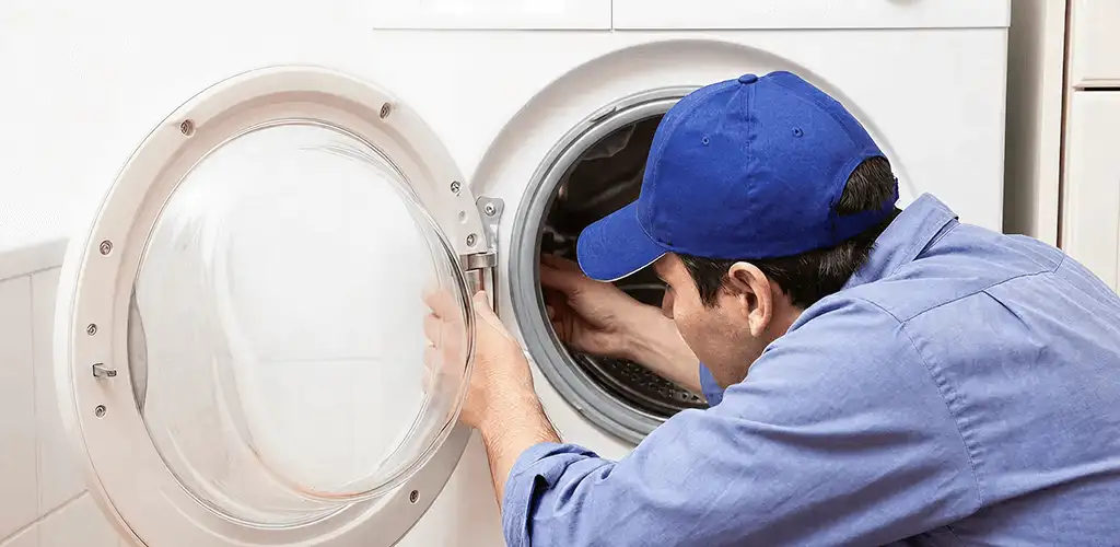 Washing machine repair handyman inspecting a front-load washer drum in Toledo, OH
