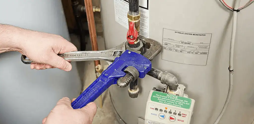Water heater repair technician tightening the shutoff valve and supply line in Toledo, OH